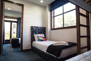 A bedroom with a bed, a window, and a door leading to another room.
