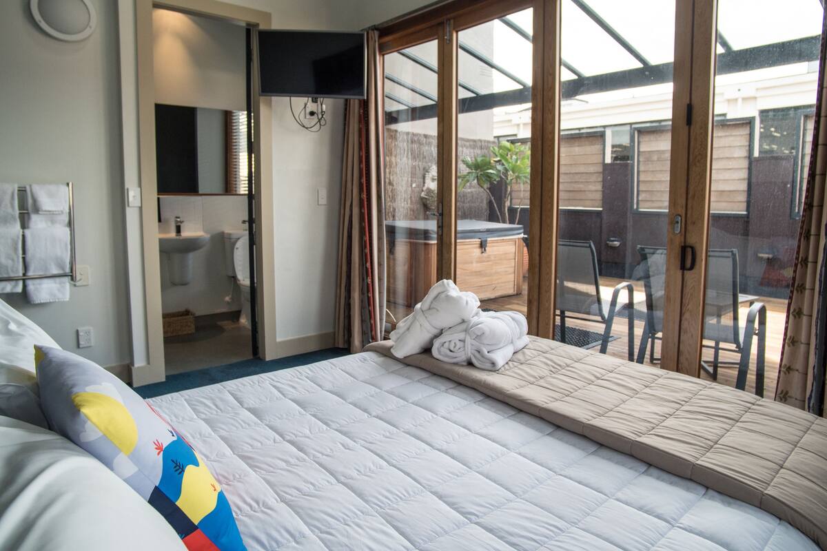 A bedroom with a bed, a bathroom, and a view of the outside.