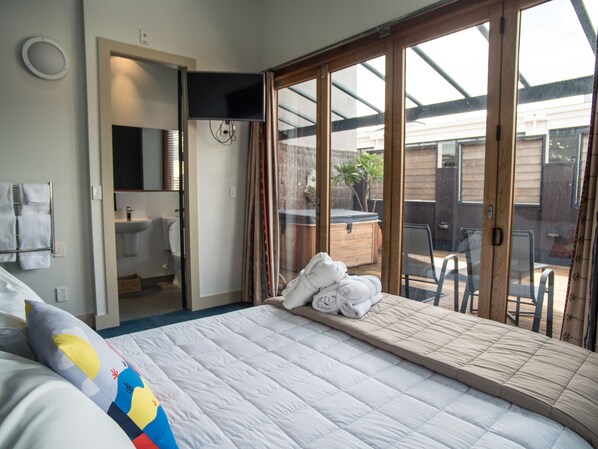 Un dormitorio con cama, baño y vistas al exterior.