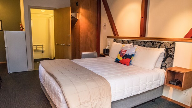 A hotel room with a large bed, a bedside table, a nightstand, a wardrobe, and a bathroom visible through an open door. - U Boutique Hotel, SureStay Collection by BW (Wellington)
