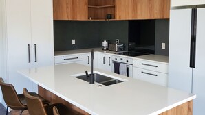 A modern kitchen with a central island, bar stools, and pendant lighting.