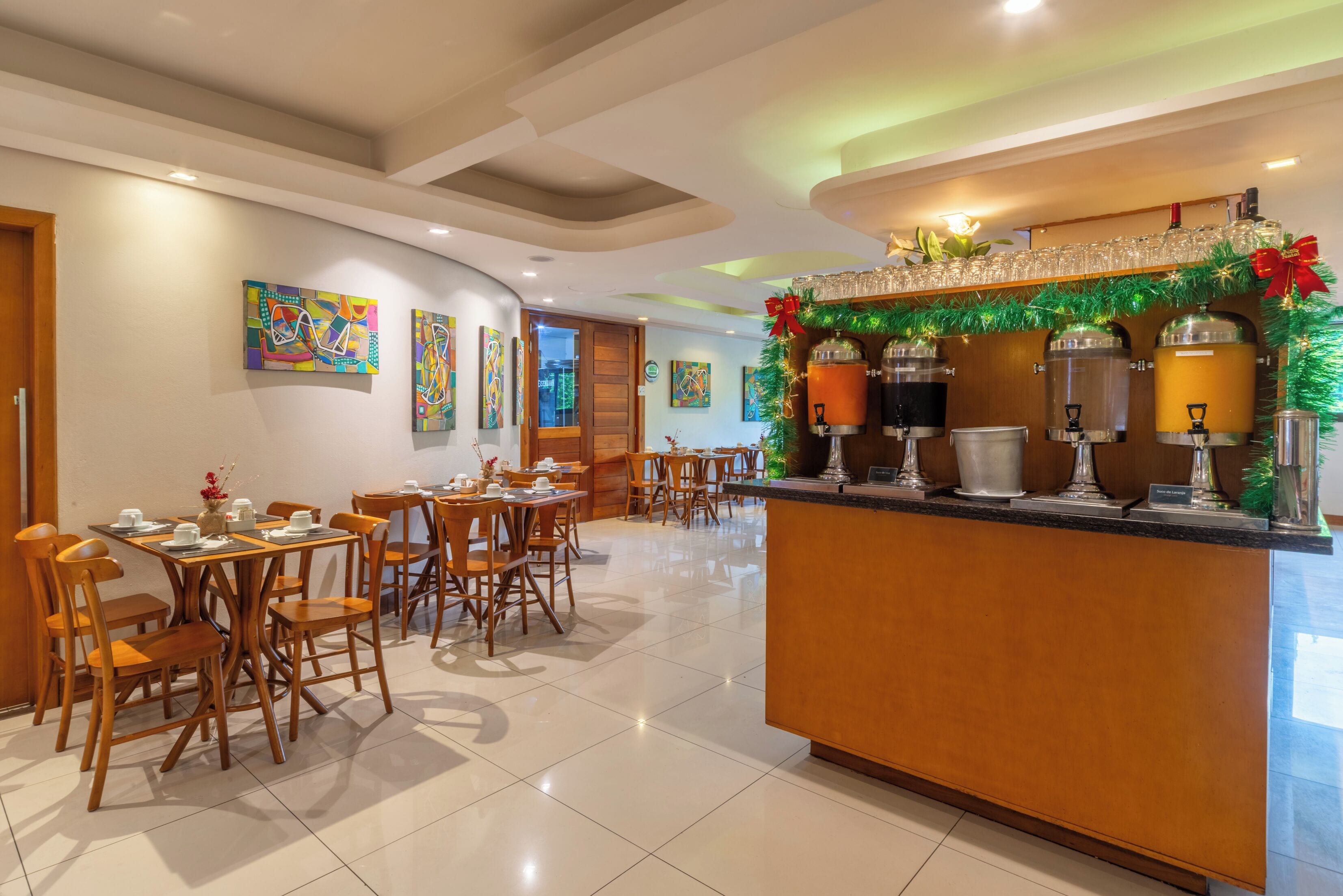 A hotel lobby with wooden furniture, a reception area with a counter, and artwork on the walls.