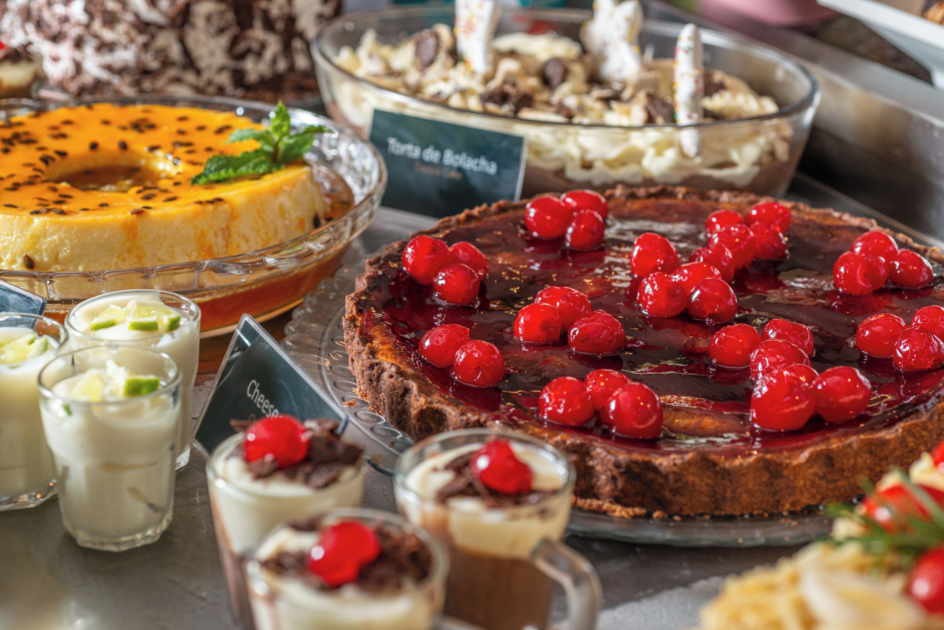 Un assortiment de desserts comprenant un gâteau au fromage, une tarte et plusieurs petites coupes de desserts.
