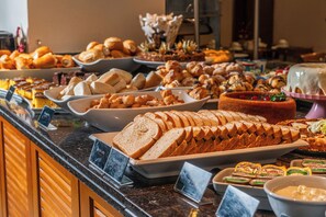 A buffet with various food items including bread, pastries, and desserts. - Hotel Laghetto Premio (Gramado)