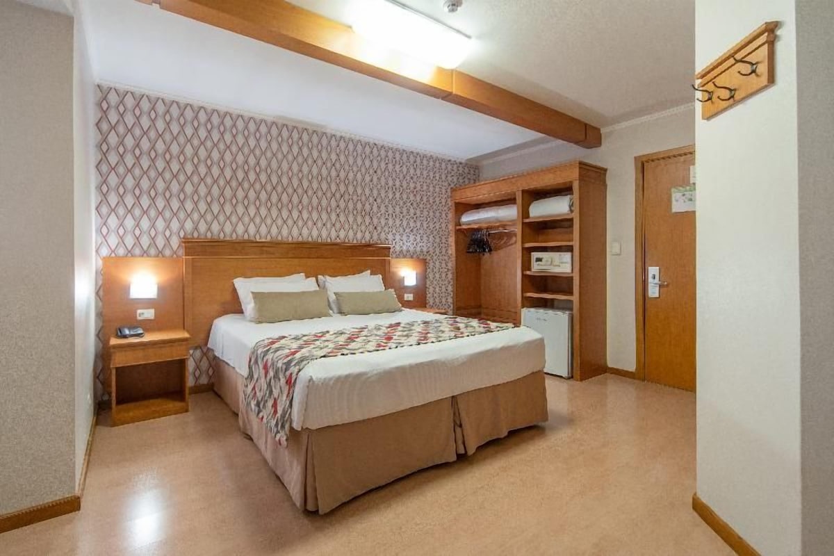 A bedroom with a bed, bedside tables, a wardrobe, and a door.