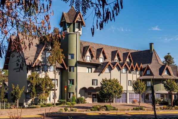 A hotel with a distinctive tower, multiple windows, and a well-maintained garden. - Hotel Laghetto Premio (Gramado)