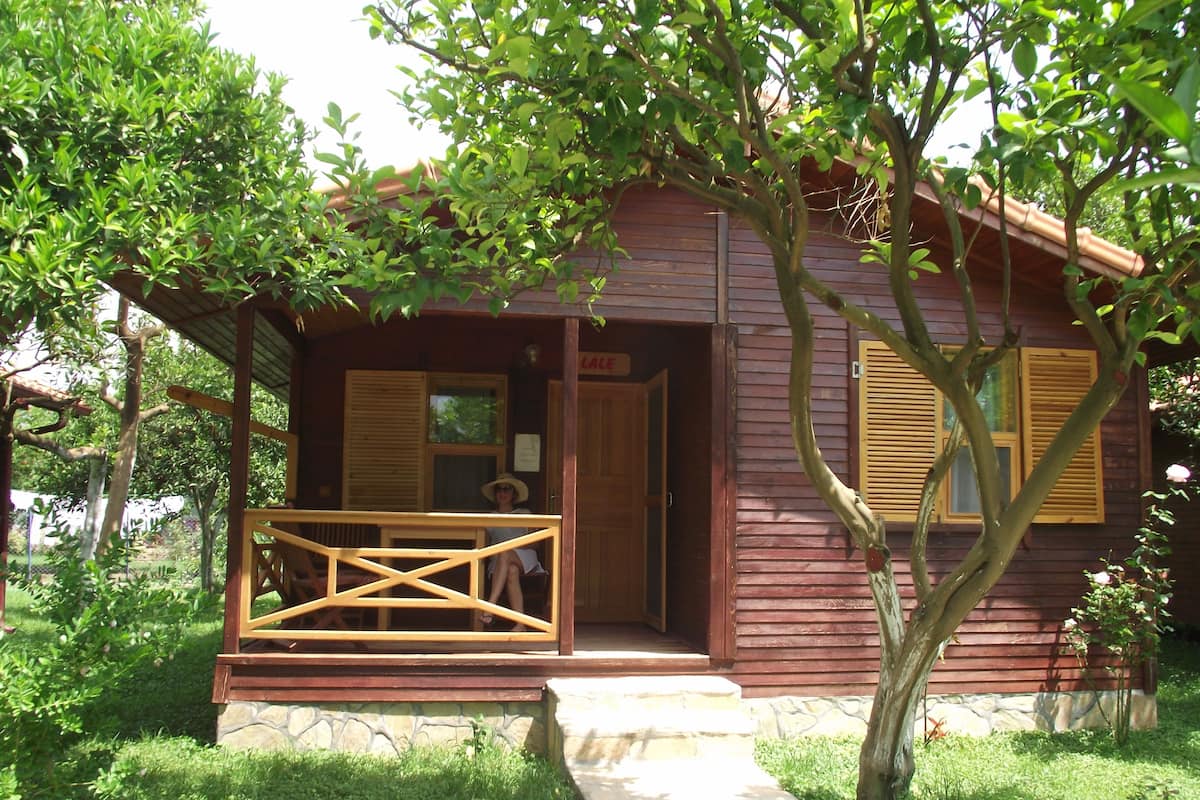 Une cabane en bois avec un porche, des marches en pierre et un petit jardin.
