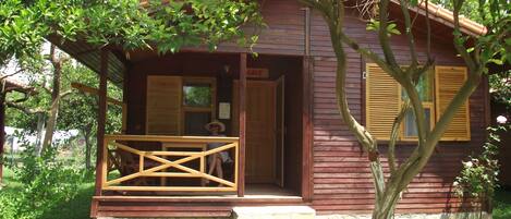 A wooden cabin with a porch, stone steps, and a small garden.