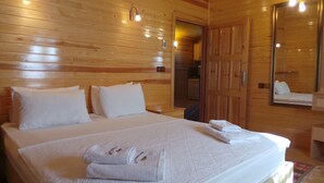 Habitación con paneles de madera, una cama, almohadas y una toalla doblada sobre la cama.