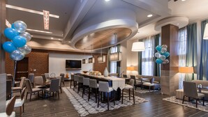 A modern hotel lobby with a bar area, seating, and a large screen. - Hampton Inn & Suites Chapel Hill-Carrboro/Downtown (Carrboro)