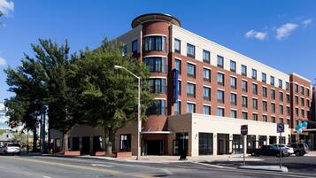 A multi-story hotel with a brick facade, large windows, and a curved corner design.