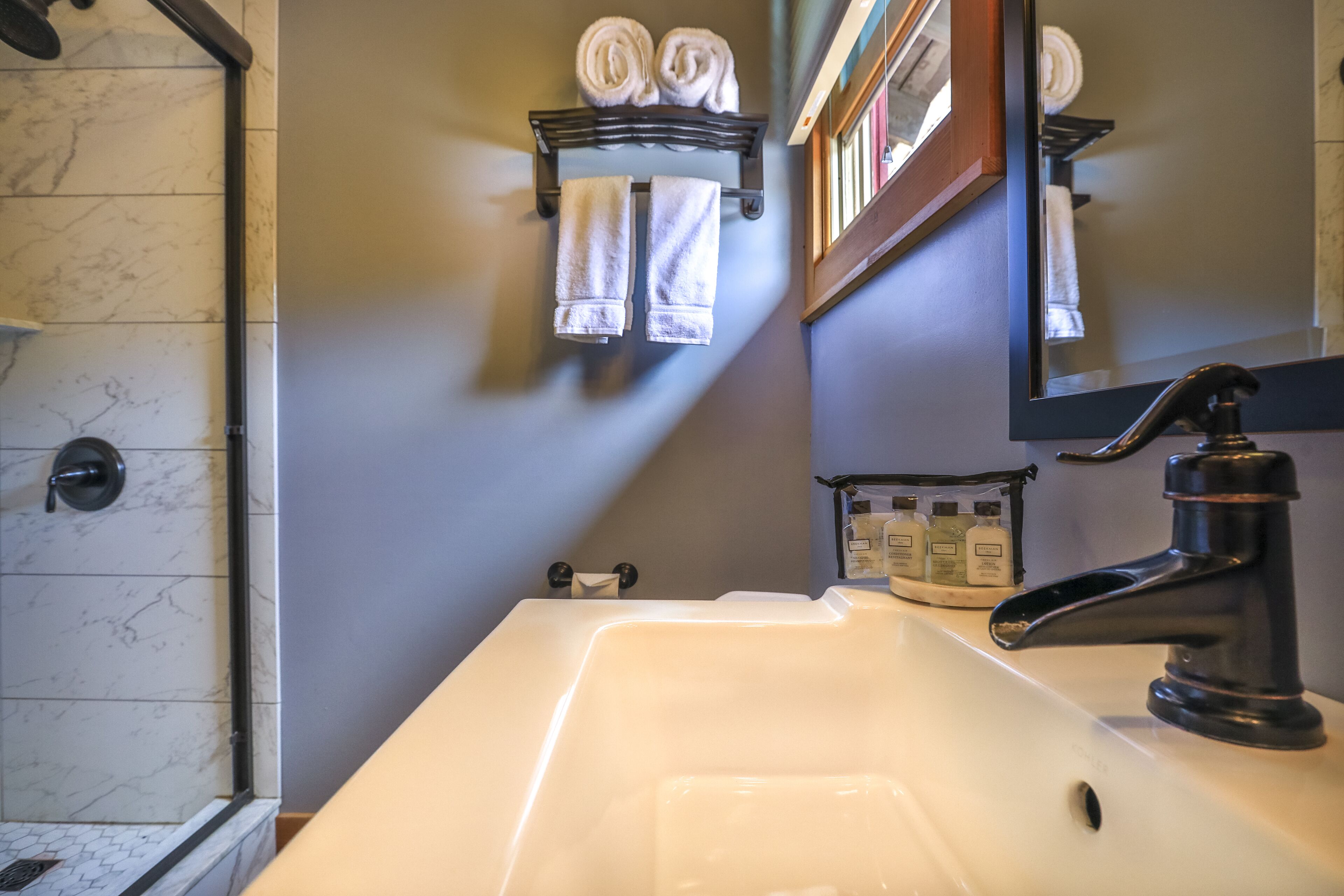 A bathroom with a white sink, dark faucet, and a towel rack with towels.