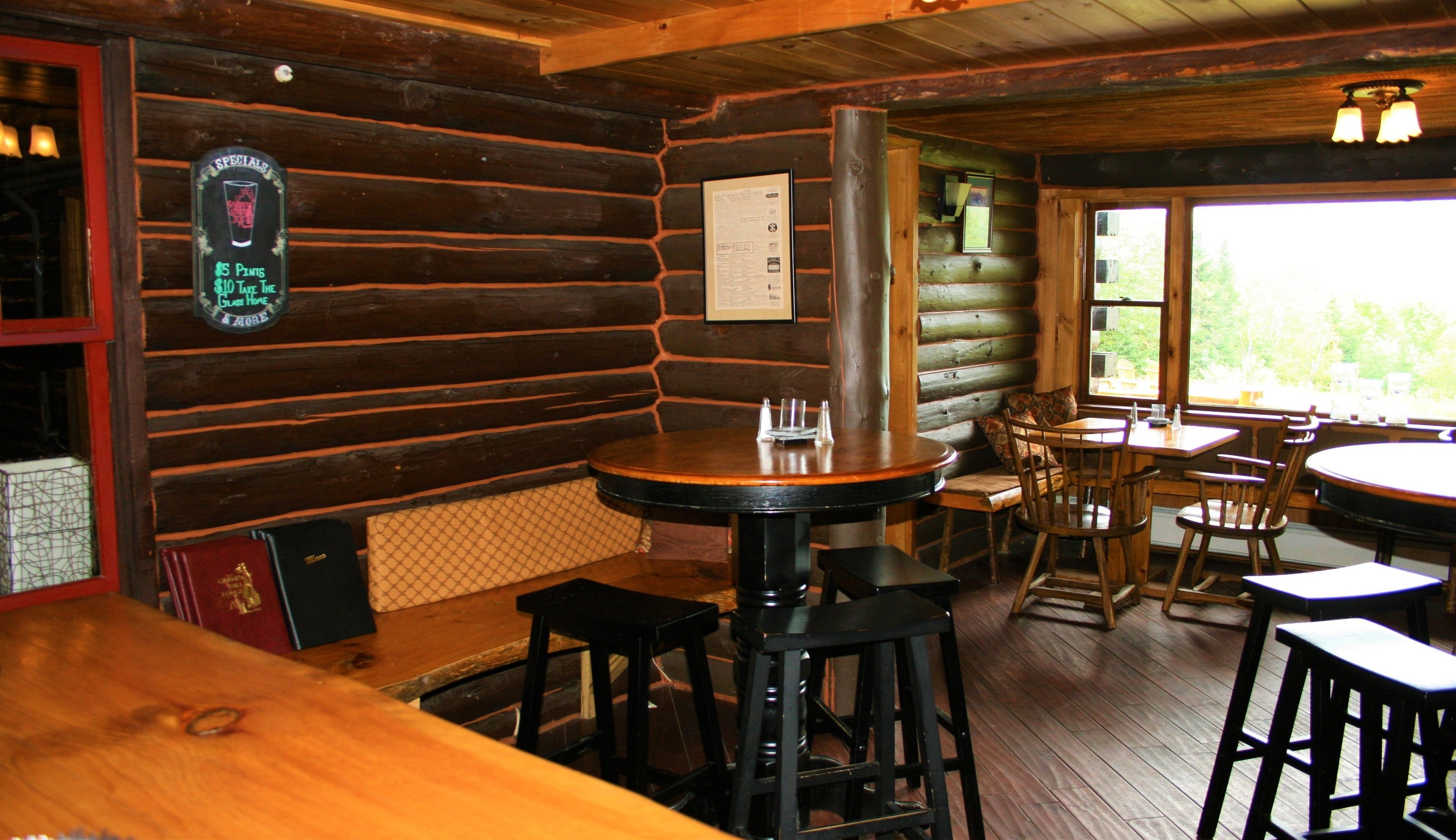 Un interior rústico de madera con una zona de bar, mesas y sillas de madera.