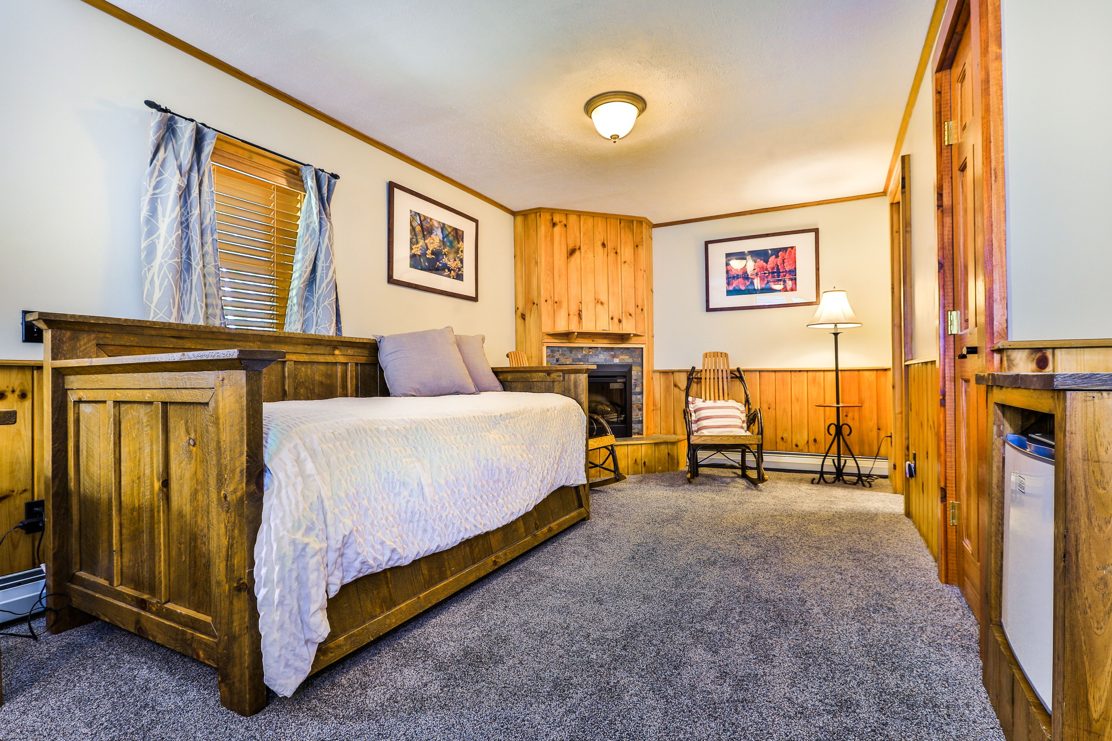 A cozy room with a wooden bed, a fireplace, a chair, and a table.