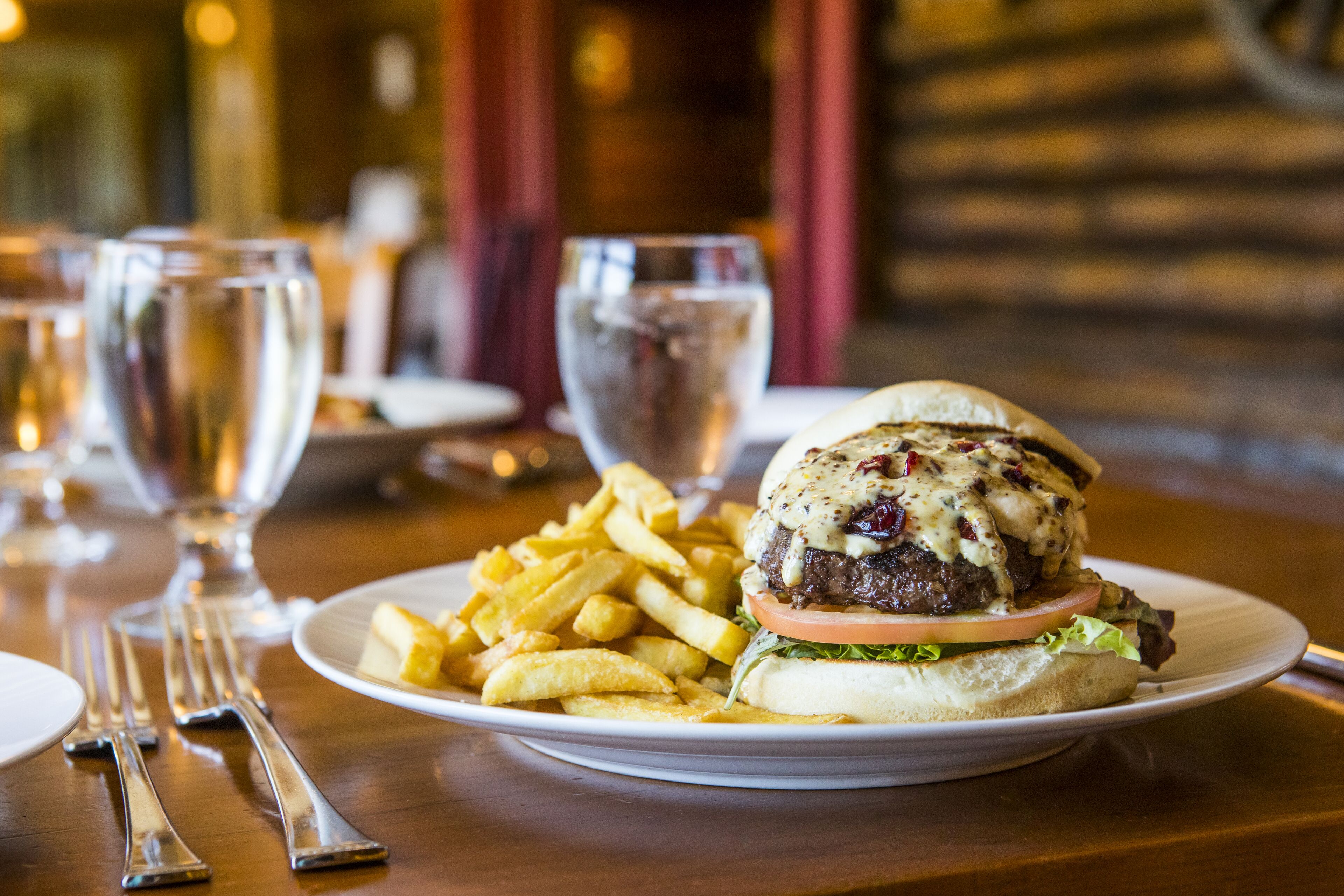 A plate with a burger and fries on a wooden table.