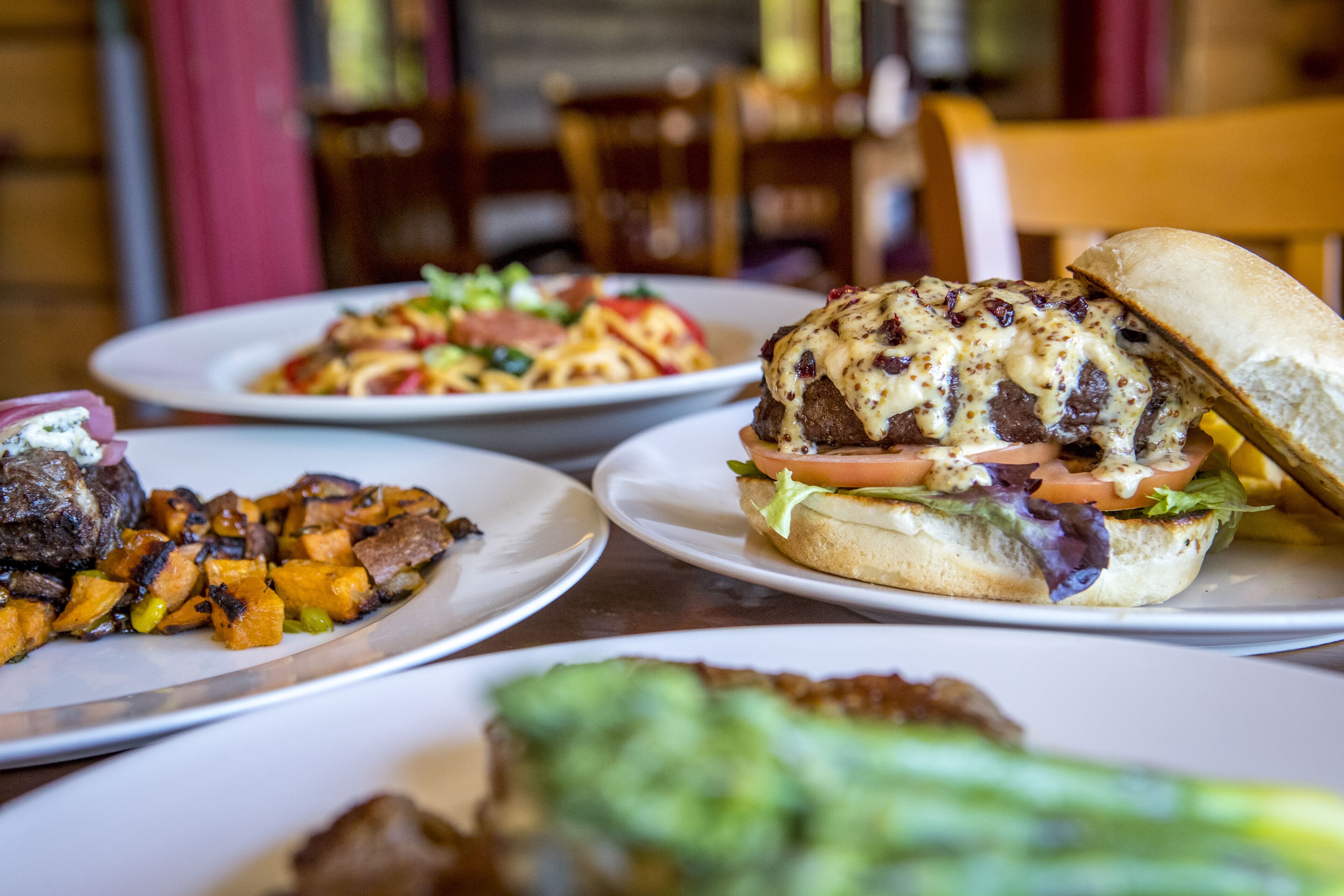 Une table à manger avec des assiettes remplies de nourriture, notamment un hamburger, des frites et une salade.