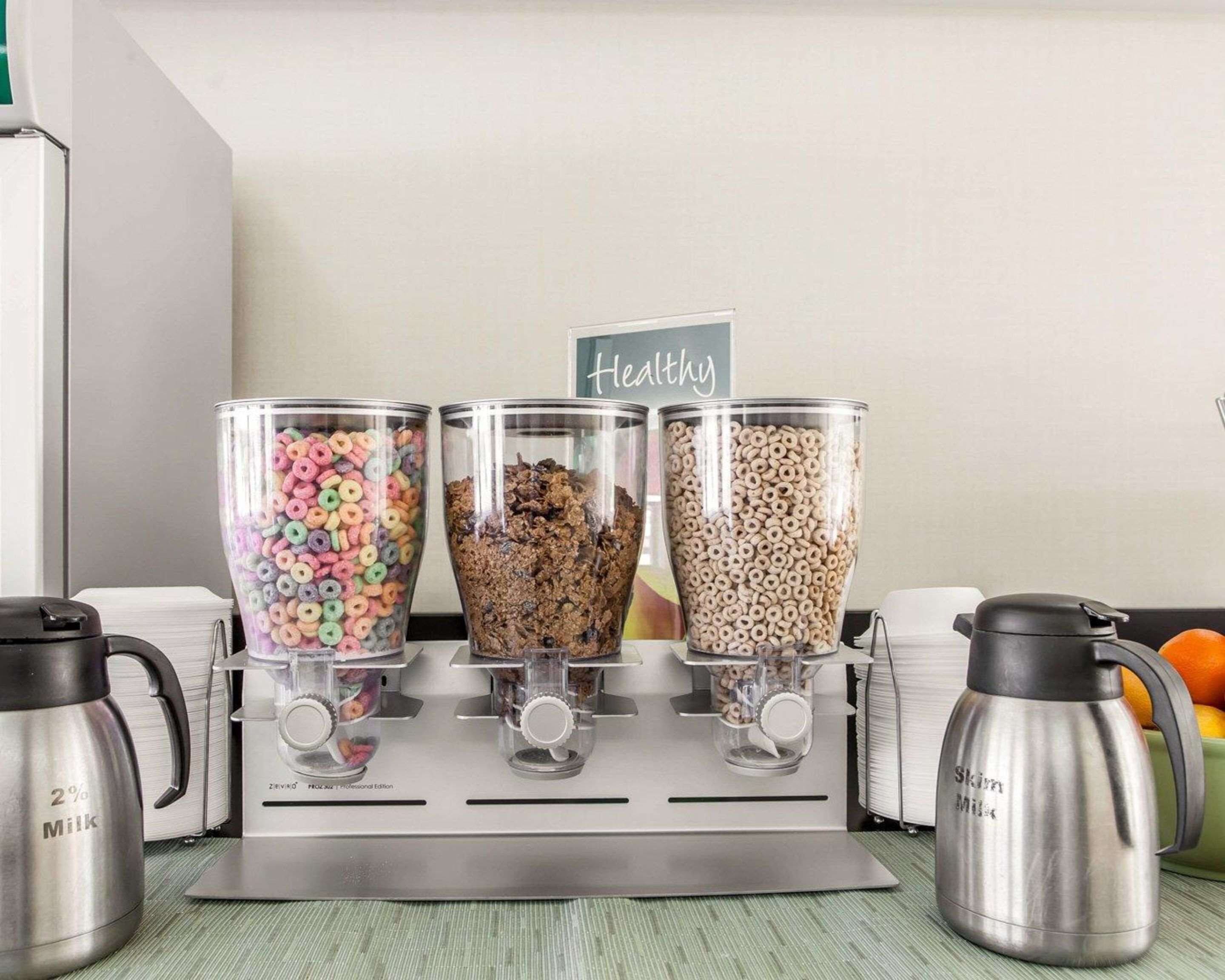 A coffee machine with three glass containers filled with different types of cereal.