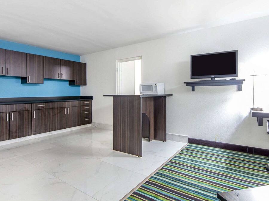 A modern kitchen with dark wood cabinets, a microwave, and a flat-screen TV mounted on the wall.