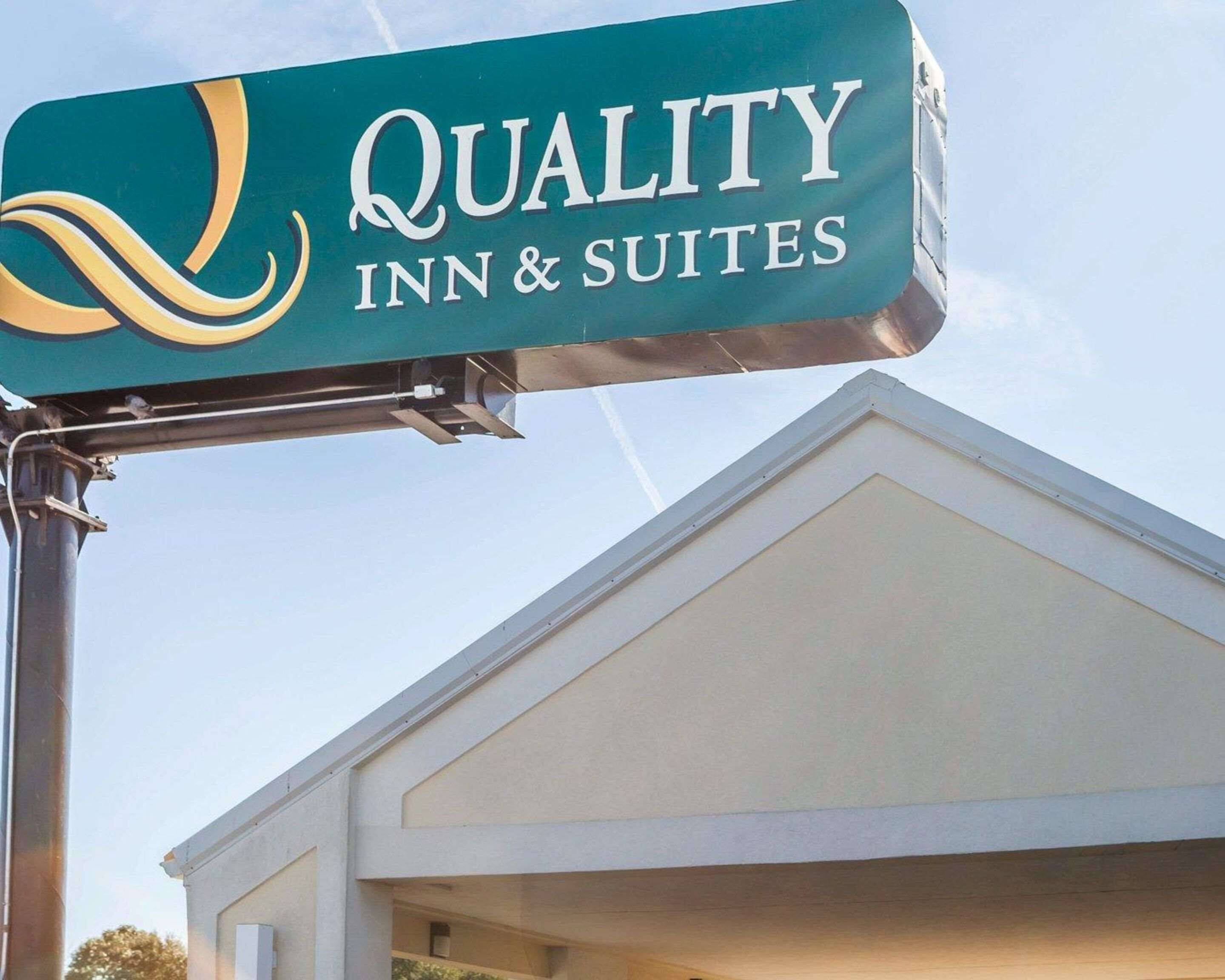 A sign for "Quality Inn & Suites" with a modern design and a clear view of the building's entrance.