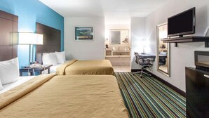 A hotel room with two beds, a desk, a chair, a television, and a bathroom visible in the background. - Quality Inn & Suites Jasper - Kimball (Jasper)