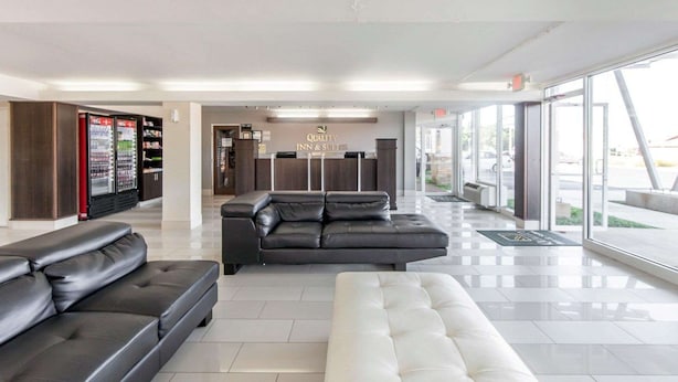 A hotel lobby with a reception desk, a seating area with leather sofas, a vending machine, and large windows offering a view of the outside. - Quality Inn & Suites Jasper - Kimball (Jasper)