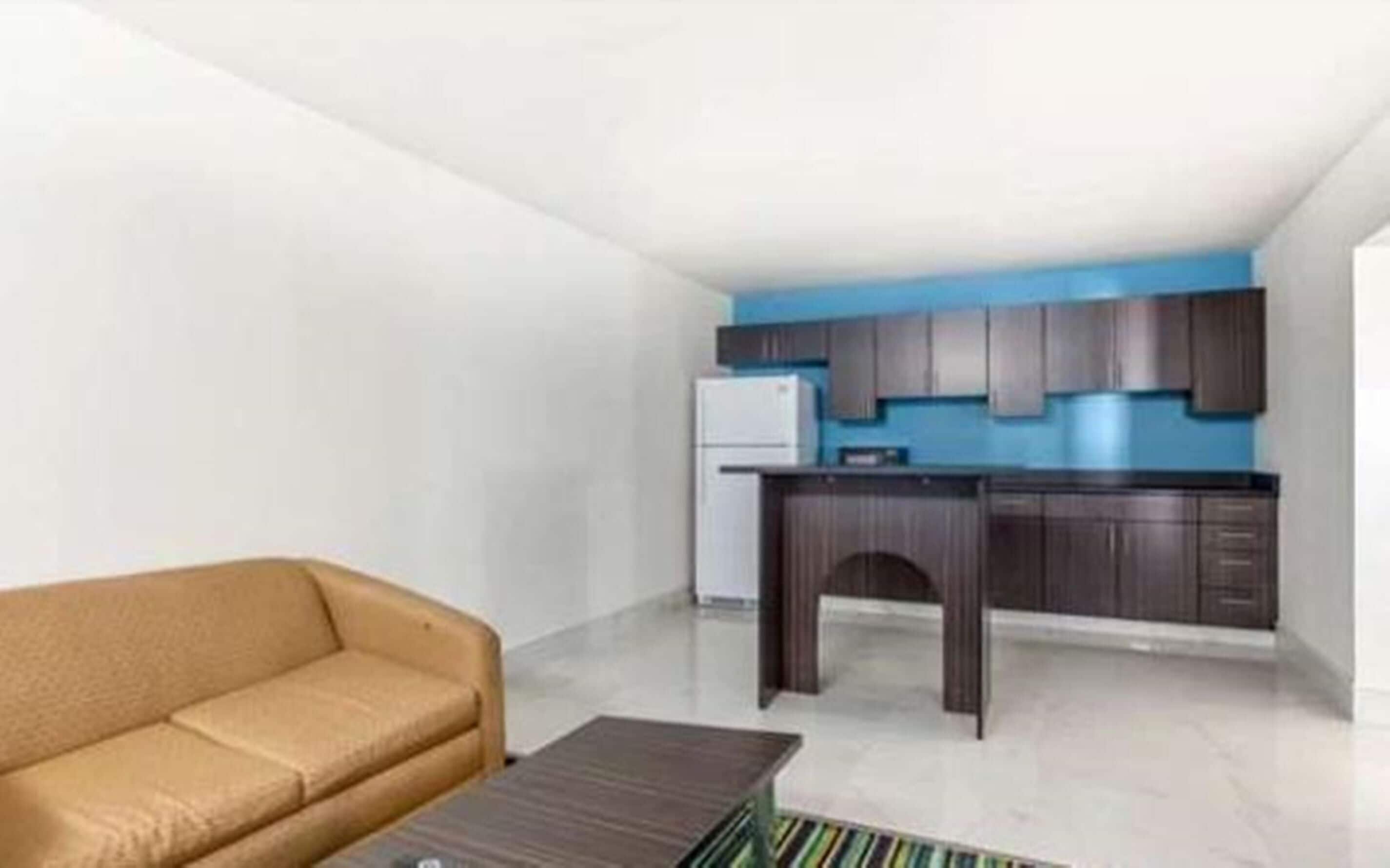 A compact living space with a kitchenette, a sofa, and a coffee table.