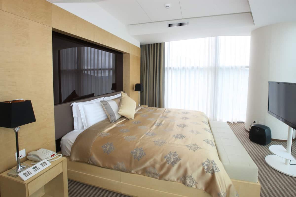 A hotel room with a bed, a TV, a phone, and a lamp.