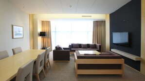 A hotel room with a dining table, chairs, a sofa, a loveseat, a coffee table, a TV, and a large window with curtains. - High1 Grand Hotel Convention Tower (Jeongseon)