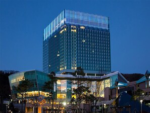 A modern high-rise building with a glass facade and a distinctive striped pattern at the top. - High1 Grand Hotel Convention Tower (Jeongseon)