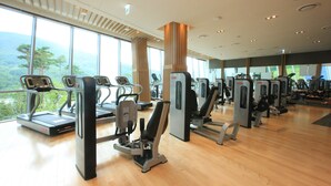 A gym with treadmills, weight machines, and a large window overlooking a mountainous landscape. - High1 Grand Hotel Convention Tower (Jeongseon)