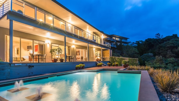 A modern house with a swimming pool, outdoor seating, and a well-lit balcony. - Decks of Paihia (Paihia)