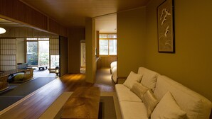 A traditional Japanese-style room with tatami flooring, a low wooden table, a sofa, and a sliding door leading to another room. - Ishibekoji Ryugin (Kyoto)