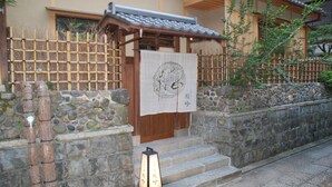 A traditional Japanese building with a wooden entrance, stone steps, and a bamboo fence. - Ishibekoji Ryugin (Kyoto)