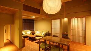 A traditional Japanese-style room with a wooden dining table, green sofa, and sliding doors. - Ishibekoji Ryugin (Kyoto)