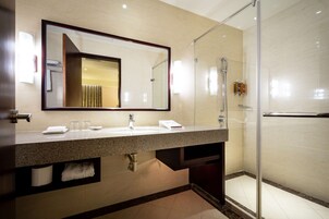 A modern bathroom with a large mirror, a sink, and a glass-enclosed shower.