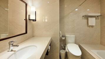 A modern bathroom with a large bathtub, a separate toilet, and a sink.