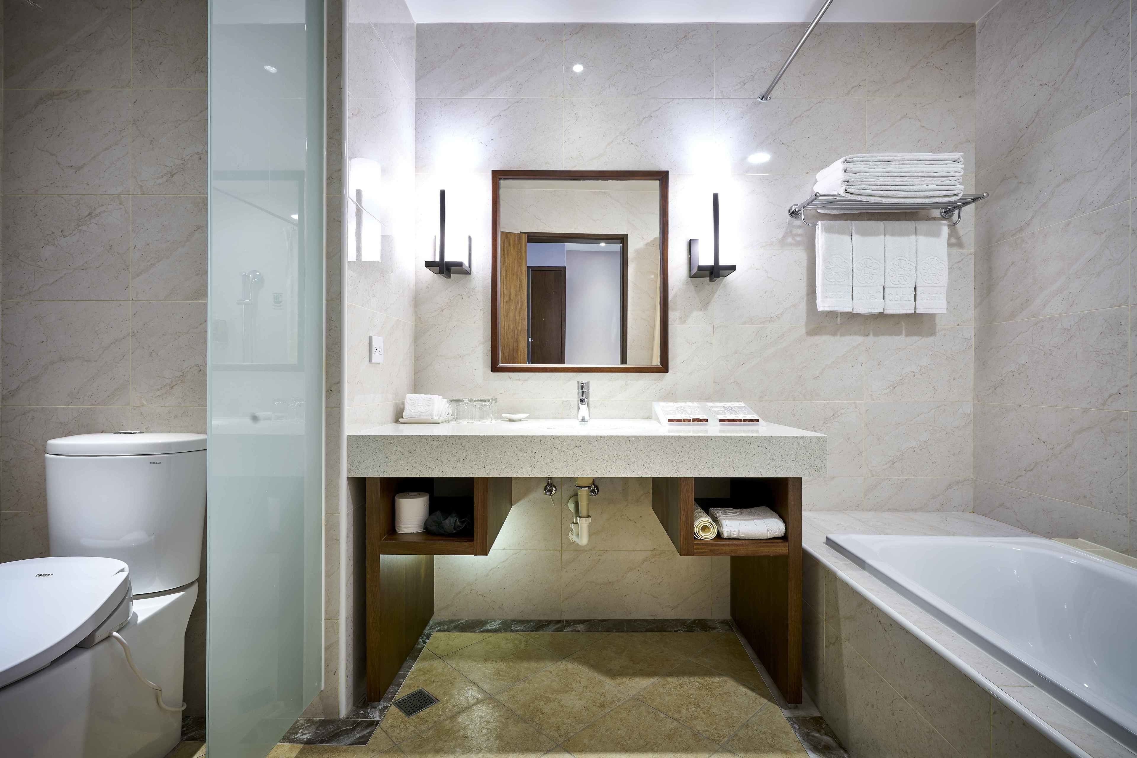 Un baño moderno con cabina de ducha de vidrio, inodoro blanco, lavabo con espejo arriba y bañera.