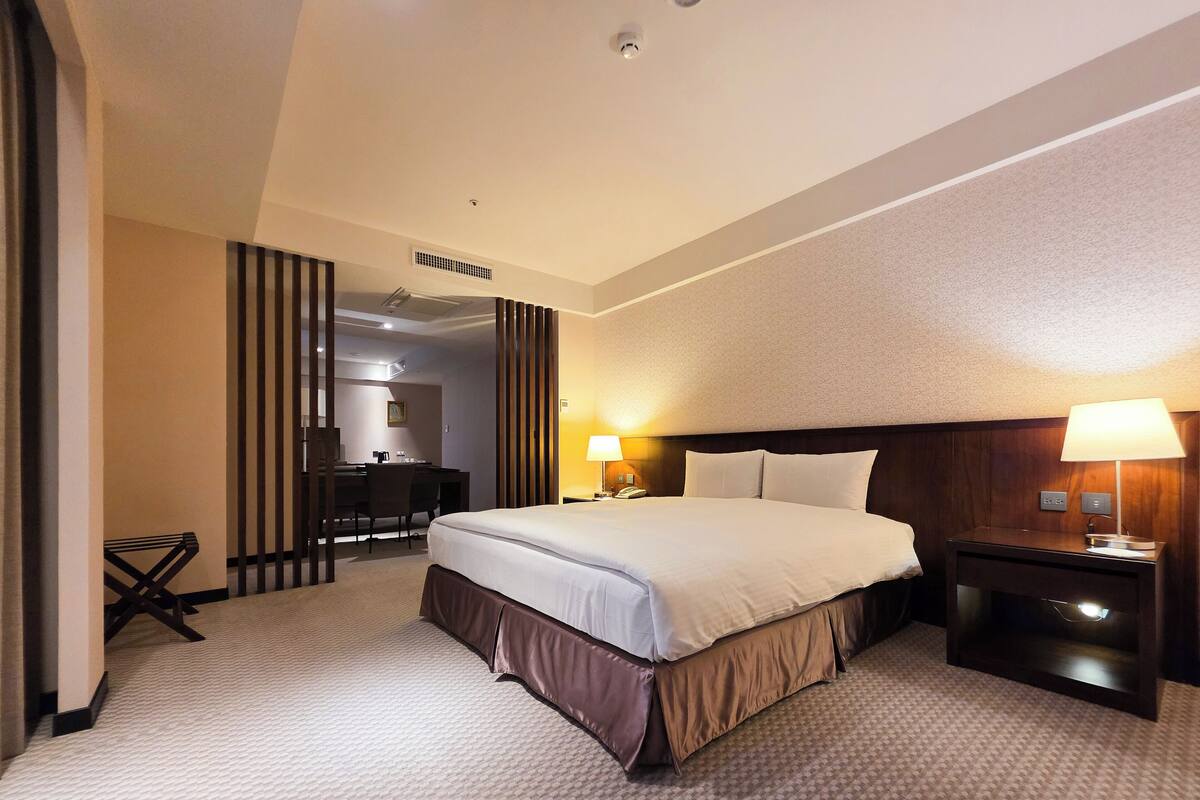 A hotel room with a large bed, bedside tables, a desk, and a chair.
