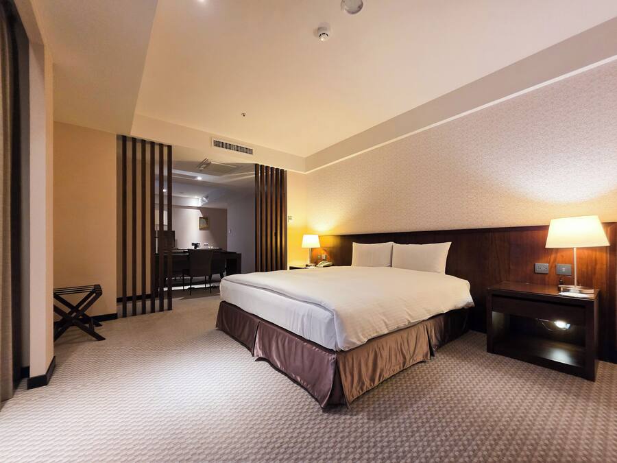 Ein Hotelzimmer mit einem großen Bett, Nachttischen, einem Schreibtisch und einem Sessel.
