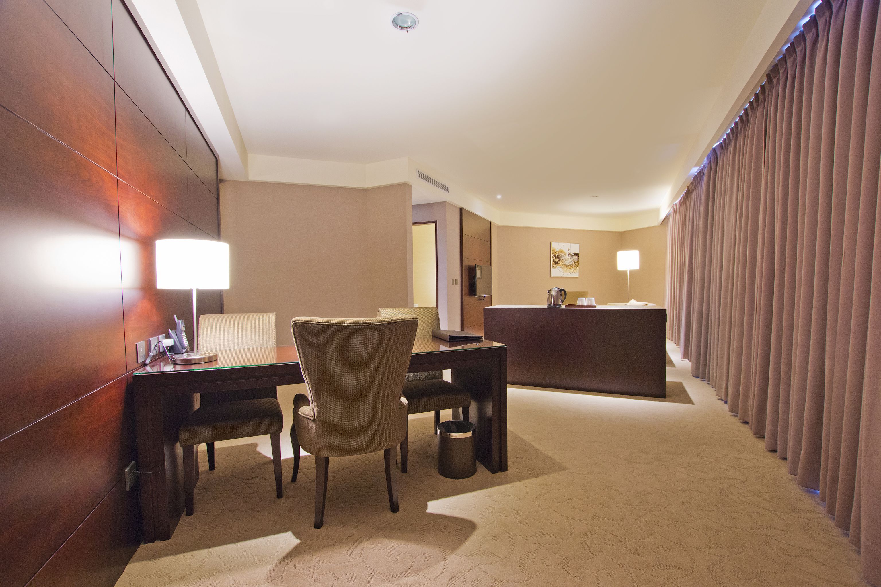 A hotel room with a desk, chair, and a minibar.