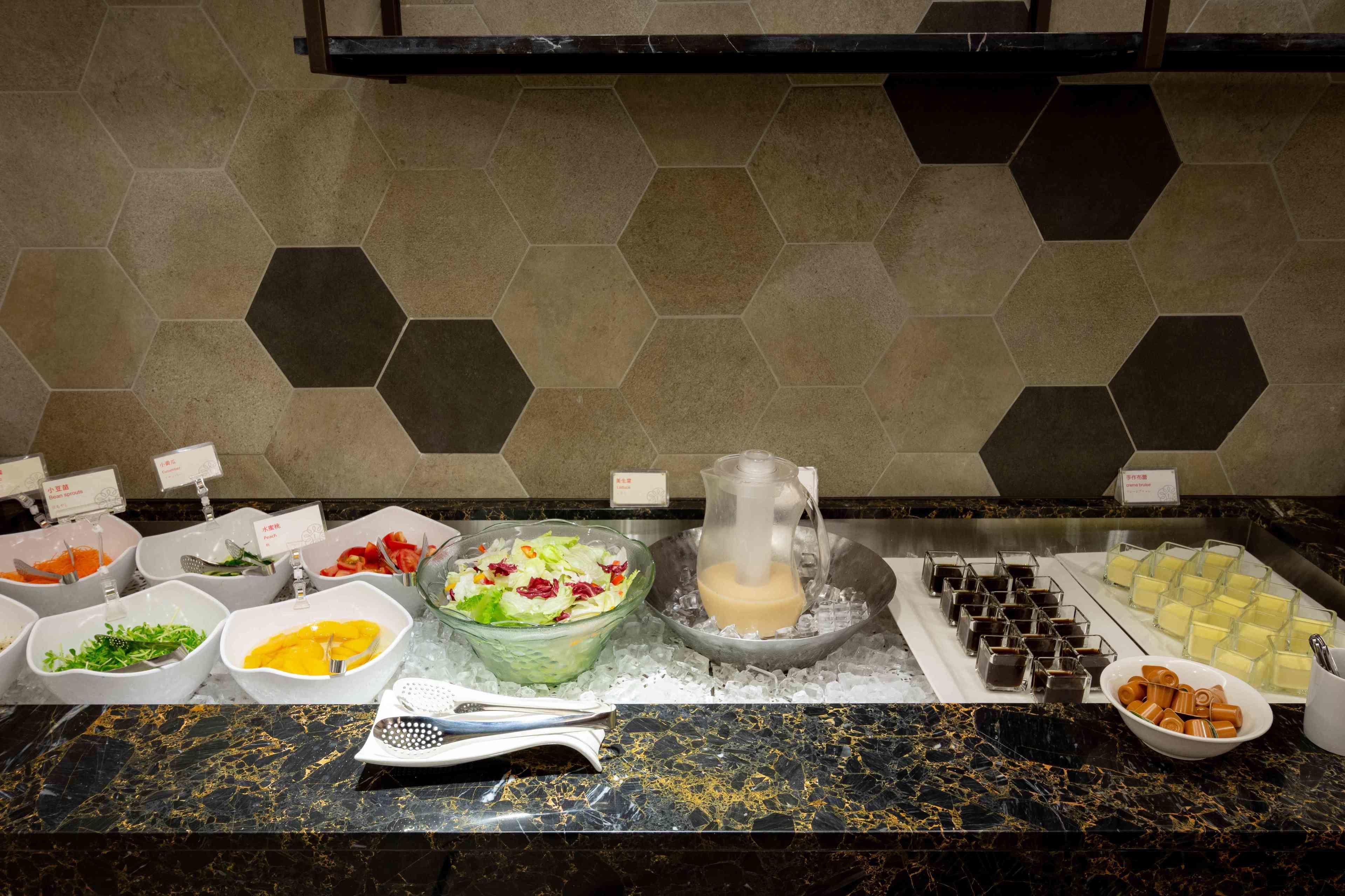 A buffet with various food items and a pitcher of milk on a marble countertop.