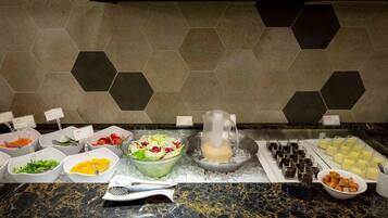 A buffet with various food items and a pitcher of milk on a marble countertop.