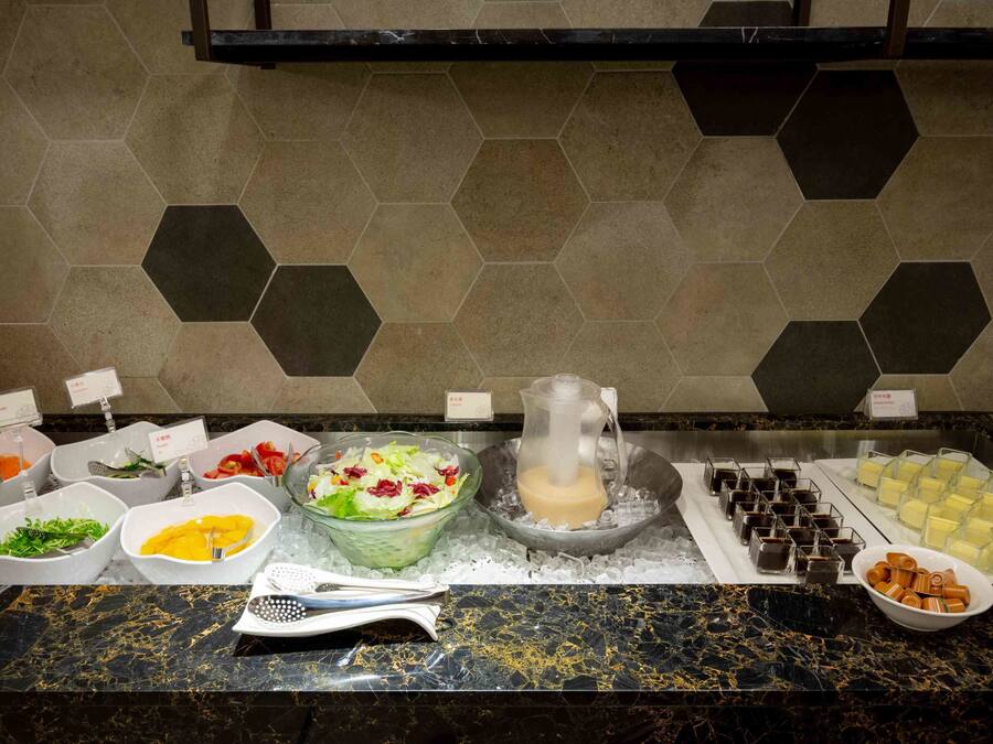 A buffet with various food items and a pitcher of milk on a marble countertop.