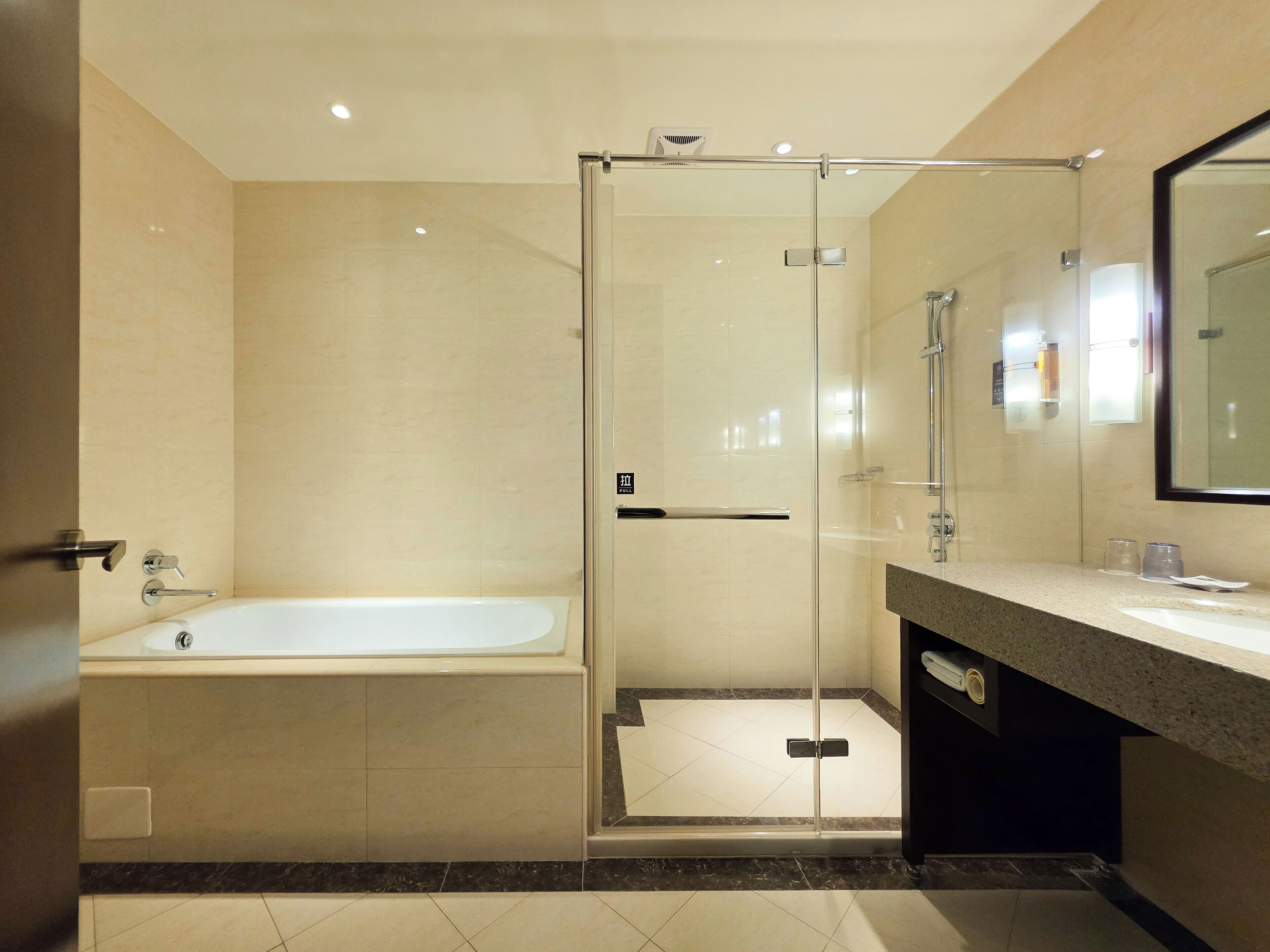 A modern bathroom with a glass-enclosed shower, a standalone bathtub, and a vanity with a mirror.