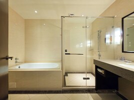 A modern bathroom with a glass-enclosed shower, a standalone bathtub, and a vanity with a mirror.