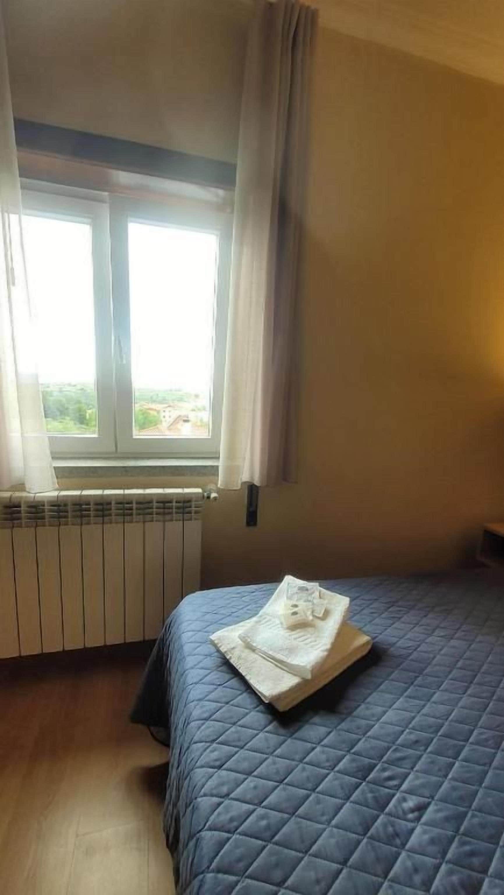 Een slaapkamer met een bed, een raam met gordijnen en een radiator.