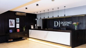 A modern hotel reception desk with a marble counter, black paneling, and a sign reading "DUOMI HOTEL". -  Duomi Hotel Buenos Aires (Buenos Aires)