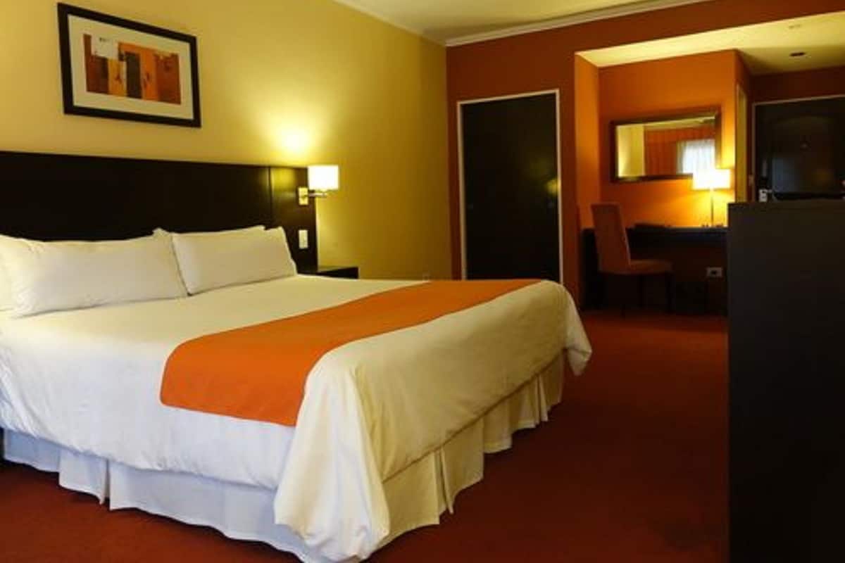 Une chambre d’hôtel avec un grand lit, un bureau et une chaise.