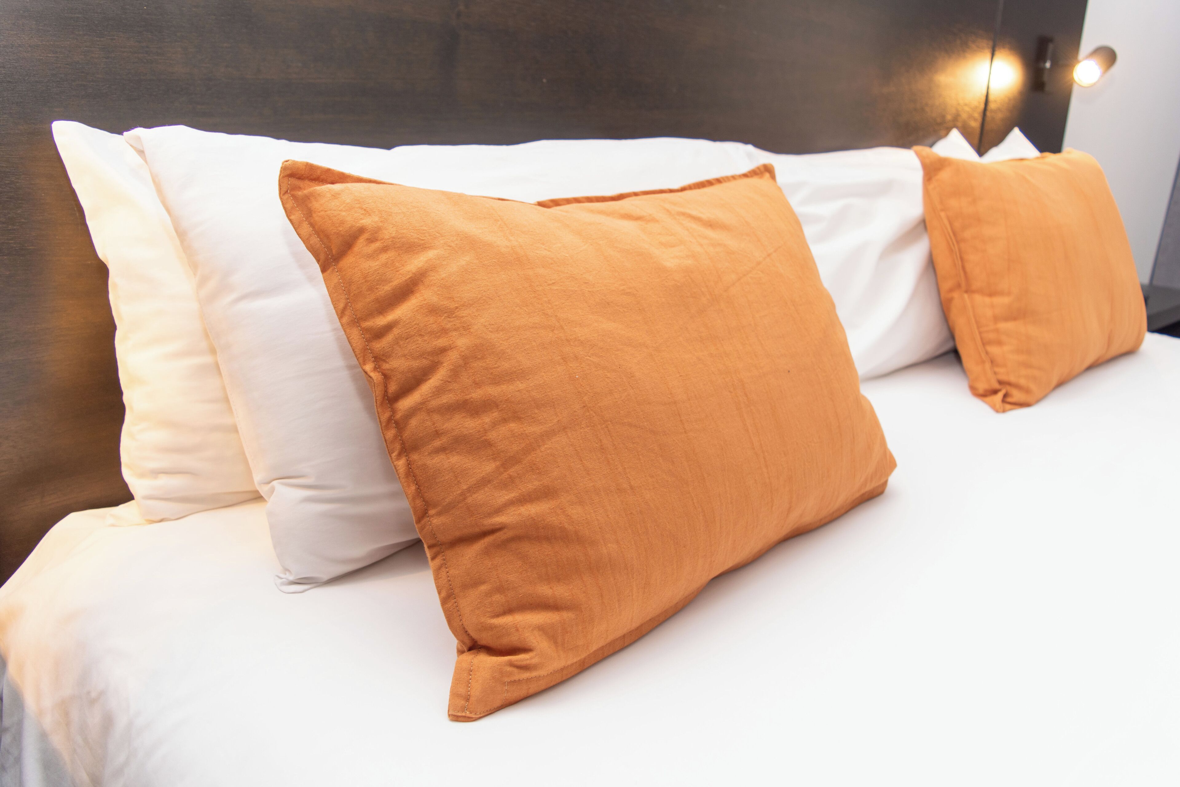 A bed with white and mustard-colored pillows.