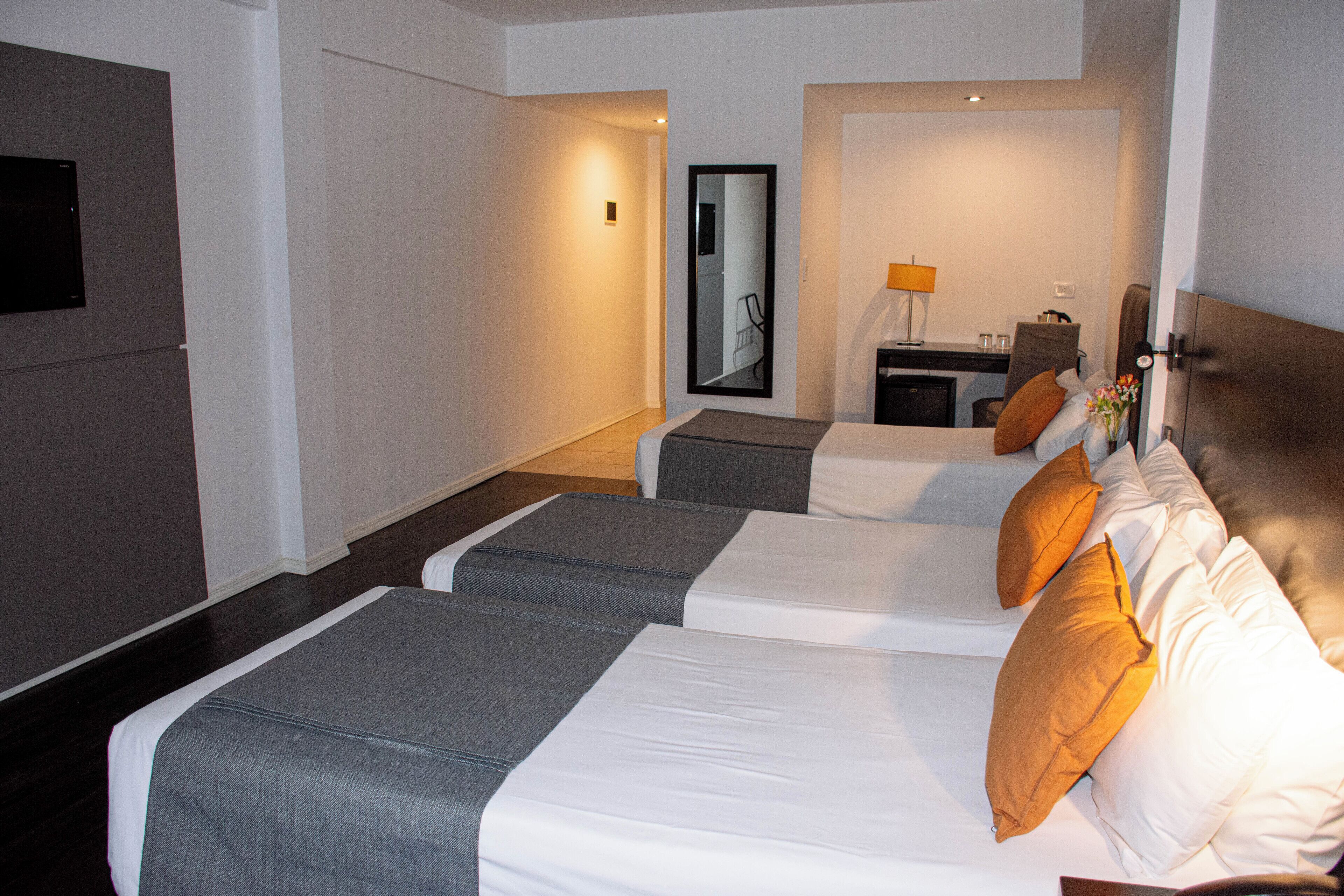 Habitación de hotel con dos camas, un escritorio y un espejo.